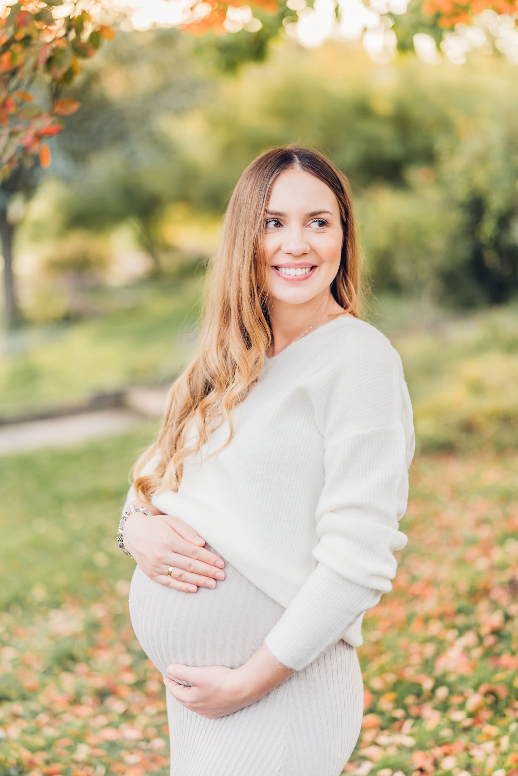 Braunhaarige schwangere Frau im Strecktal Park Pirmasens beim Babybauchshooting in hellen beigen Klamotten